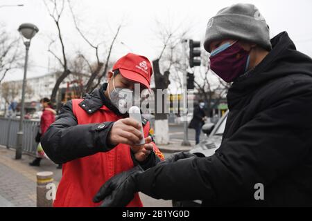 Pékin, Chine. 27 février 2020. Le volontaire Zhang Jianguo (L) prend la température d'un résident à l'entrée de Cheniandian Lane à Beijing, capitale de la Chine, 27 février 2020. Crédit: Ju Huanzong/Xinhua/Alay Live News Banque D'Images