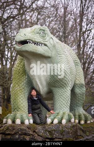 Verena McCaig, de l'Angleterre historique, avec une sculpture d'Iguanadon, faisant partie des dinosaures du Crystal Palace, dans le Crystal Palace Park, Londres. Les statues de classe I de 30 ans, construites dans les années 1850, ont été ajoutées au registre du patrimoine historique de l'Angleterre à risque après que les experts ont trouvé de grandes fissures sur les corps et les membres et en danger de perdre des orteils, des dents et des queues. Banque D'Images