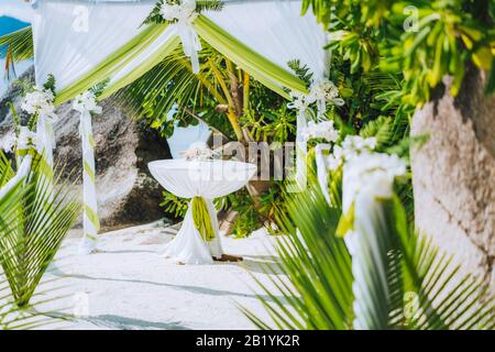 Décoration romantique mariage lieu, table et chaises sur la plage tropicale. Feuillage vert luxuriant et baisse de blanc Banque D'Images