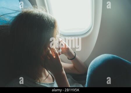 Petite fille ayant une oreille pop sur l'avion pendant le décollage. Banque D'Images