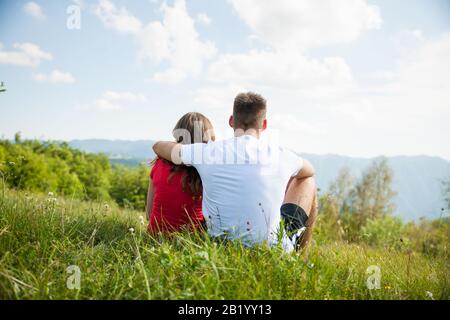 le couple actif repose sur un sommet de montagne regardant sur un paysage de montagne Banque D'Images