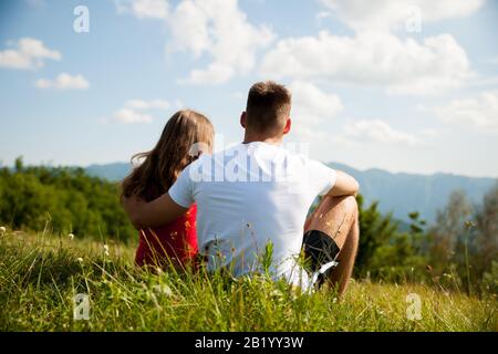 le couple actif repose sur un sommet de montagne regardant sur un paysage de montagne Banque D'Images