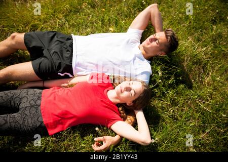 le couple actif repose sur un sommet de montagne regardant sur un paysage de montagne Banque D'Images