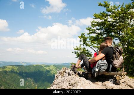 le couple actif repose sur un sommet de montagne regardant sur un paysage de montagne Banque D'Images