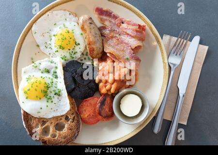 Petit déjeuner anglais complet avec œufs frits, saucisses, haricots, champignons, tomates grillées et bacon sur fond gris du plan d'examen. Vue de dessus. Banque D'Images