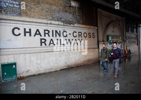 Les gens marchent devant de vieux panneaux pour la gare de Blackfriars et la compagnie de chemin de fer de Charing Cross le 27 novembre 2019 à Londres, Angleterre, Royaume-Uni. La compagnie de chemin de fer Charing Cross a été créée en 1859 afin de construire une extension reliant la gare de Waterloo. Banque D'Images