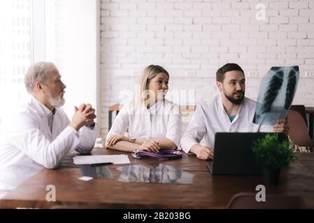 Un groupe de trois médecins adultes et jeunes discute des rayons X de la poitrine Banque D'Images