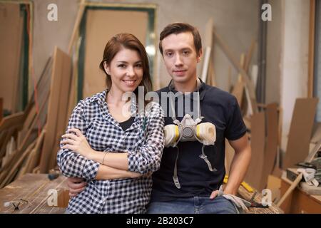 Couple souriant joiners assis en atelier sur fond de planches Banque D'Images