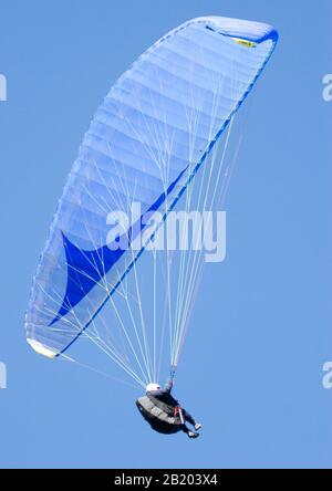 un homme dansait d'un parapente lors d'une journée ensoleillée avec un ciel bleu clair Banque D'Images