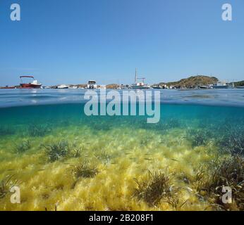 Espagne Méditerranée, bateaux amarrés dans la baie de Port Lligat et petits poissons avec algues et de la mer sous l'eau, vue partagée sur et sous la surface de l'eau Banque D'Images