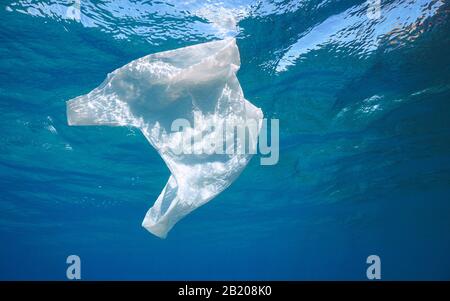 Pollution plastique dans l'océan, un sac en plastique blanc coule sous la surface de l'eau Banque D'Images