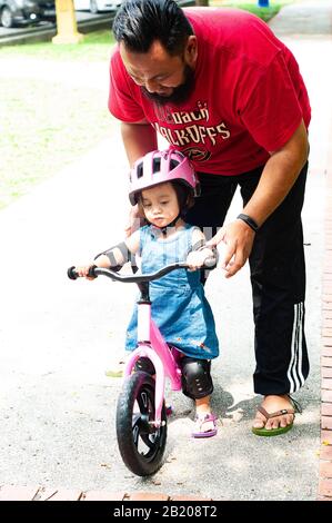 Jeune père de passer du temps avec Mignon Asian 2 ans bébé fille enfant, père et enfant s'amusant avec balance Bike (vélo de course) sur la nature, papa te Banque D'Images