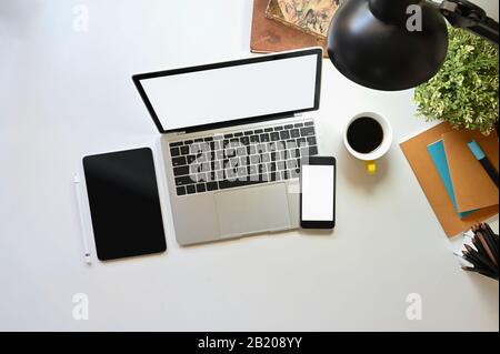 Vue de dessus d'un ordinateur portable avec écran blanc vierge, combiné avec tablette noire à écran vide, smartphone blanc à écran vide, ordinateur portable, potted p Banque D'Images