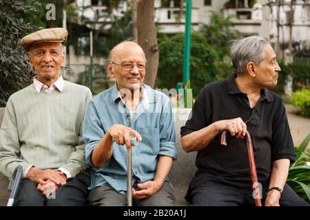 Bengaluru, INDE - 25 juin 2010. Les hommes indiens heureux se détendent sur un banc de parc à Bangalore, en Inde Banque D'Images