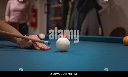 Main d'un homme jouant au billard. La boule blanche domine l'image Banque D'Images