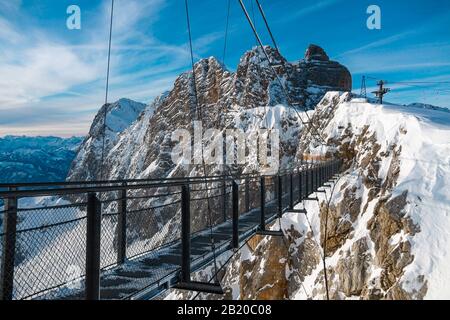 Pont suspendu dans les Alpes autrichiennes au sommet du glacier de Dachstein pendant une journée ensoleillée en hiver. Station de ski vide et beau temps. Banque D'Images