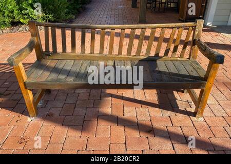 un banc de jardin en bois de style rétro au lever du soleil le matin sur un trottoir orné de pavés Banque D'Images