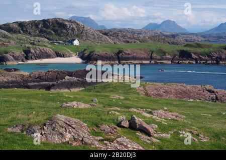 En regardant vers la baie de Clachtol, la péninsule de Stoer, en Écosse, à bord d'un bateau à vitesse qui approche la plage avec des montagnes en arrière-plan Banque D'Images