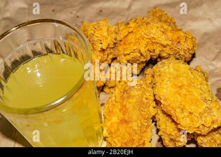 Ailes de poulet panées et un verre de limonade sur fond de papier gris. Gros plan Banque D'Images