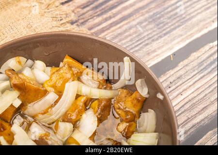 Champignons salés avec oignons dans un bol en céramique sur fond de bois. Gros plan Banque D'Images