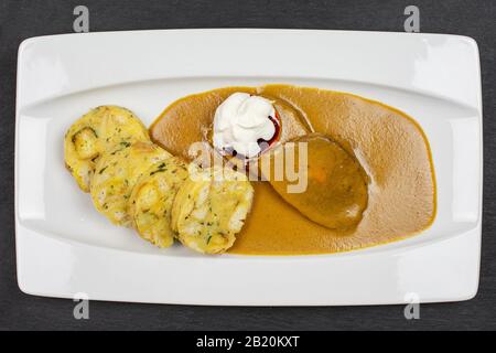 Belle cirloine de boeuf avec sauce à la crème de légumes racines avec des boulettes de carlsbad sur plaque rectangulaire blanche en céramique flatlay sur la pierre grise Banque D'Images