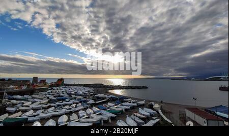 Ciel nuageux avec soleil sur la plage de Gênes avec bateaux en hiver, Italie. Banque D'Images