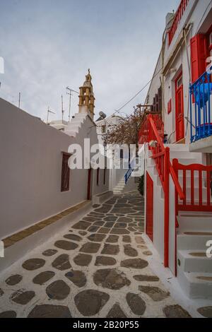 Rue Pavée étroite sur l'île de Mykonos avec bâtiments architecturaux traditionnels, maisons, boutiques, cafétérias et églises pendant une saison non touristique. Banque D'Images