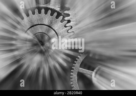 Photographie noir et blanc. Roues À Crémaillère en métal dans le mécanisme de l'horloge , poutres solaires abstraites, concept Movement est la vie, travail d'équipe , Idea Technology, Infinity, Banque D'Images