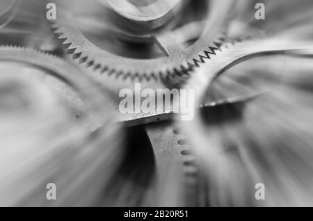 Photographie noir et blanc. Roues À Crémaillère en métal dans le mécanisme de l'horloge , poutres solaires abstraites, concept Movement est la vie, travail d'équipe , Idea Technology, Infinity, Banque D'Images