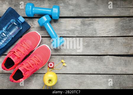 Composition avec des chaussures de sport sur fond de bois, haltères, eau de pomme dans une bouteille, joueur Banque D'Images