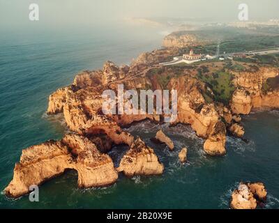 Photo aérienne au-dessus de la vue sur le promontoire de Ponta da Piedade avec groupe de formations rocheuses falaises jaunes-dorées le long de la côte calcaire, Lagos Town Portugal Banque D'Images