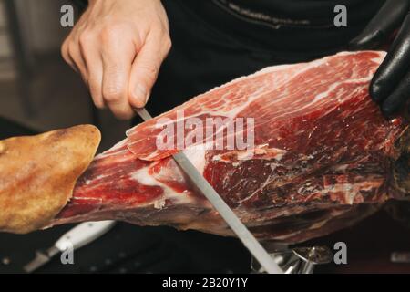 Stock photo d'une main d'un maître de jambon ibérique Cutter. Il coupe le jambon ibérique Banque D'Images