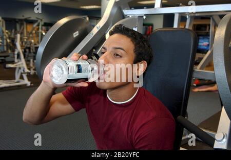 Austin, Texas : l'adolescent hispanique boit de la boisson de sport Powerade pour s'hydrater pendant une séance d'entraînement dans un centre de fitness. ©Bob Daemmrich Banque D'Images