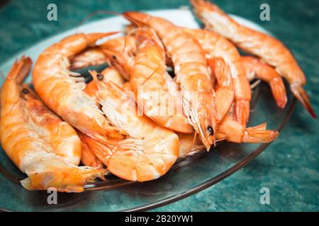 crevettes cuites sur des feuilles de laitue dans une assiette blanche prête à être servie Banque D'Images