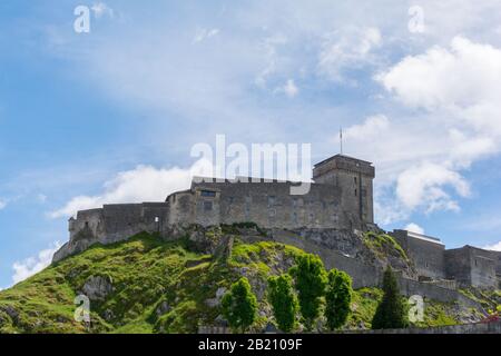 Château Fort De Lourdes. Château sur un rocher. Sommets enneigés. Ciel bleu avec nuages blancs. Ville dans les Hautes-Pyrénées, France Banque D'Images