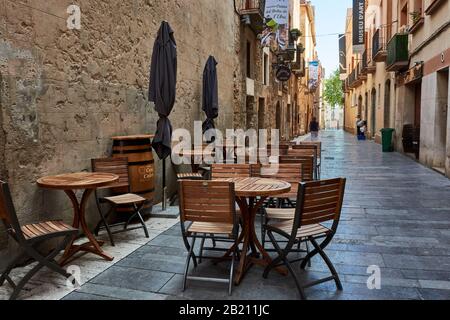 Tarragone, ESPAGNE - 12 MAI 2017: Tables et chaises de bar local dans une rue étroite de la ville de Tarragone. Banque D'Images