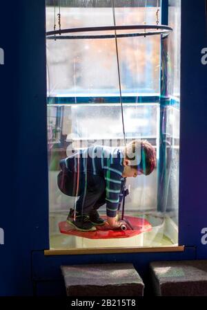 Un jeune garçon se tient sur une plate-forme À L'INTÉRIEUR d'une bulle de savon géante, créant une expérience scientifique dans ce musée des enfants Banque D'Images