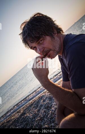 Charmant homme d'âge moyen avec un siège de cigare sur la plage tandis que couchers de soleil / gros portrait Banque D'Images