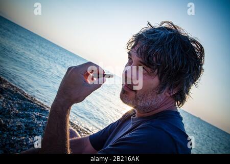 Charmant homme d'âge moyen avec un siège de cigare sur la plage tandis que couchers de soleil / gros portrait Banque D'Images