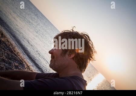 Charmant homme d'âge moyen avec un siège de cigare sur la plage tandis que couchers de soleil / gros portrait Banque D'Images