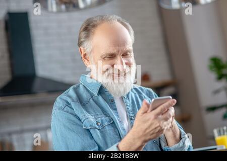 Homme âgé souriant utilisant son nouveau smartphone Banque D'Images