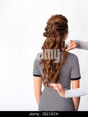 Coupe des boucles d'ondes. Coiffeuse coiffeuse coiffante de cheveux brun rouge avec cheveux longs à l'aide d'un sabot sur fond blanc. Coiffure professionnelle Banque D'Images