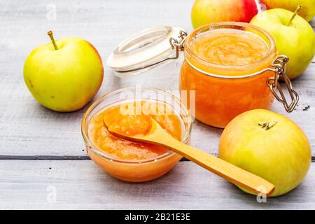 Confiture de pommes, confiture, chutney dans un pot en verre. Concept de préservation maison. Avec des pommes fraîches, une cuillère rustique sur fond de planches en bois gris, près de u Banque D'Images