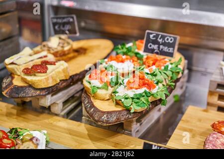 Bruschetta avec prosciutto, basilic, parmesan et tomates séchées au soleil. Marché alimentaire de rue à Florence, Italie. Divers en-cas et antipastis sur la table. Banque D'Images