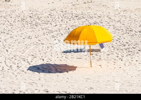 Bord de mer, plage de Floride pendant la journée ensoleillée dans le village de ville avec vue à angle élevé de parapluie jaune et ombre sur le sable Banque D'Images