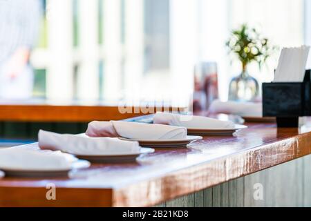 Table de bar de restaurant de fruits de mer en Floride avec clôture de assiettes et de serviettes pour servir et arrière-plan avec plantes sur le comptoir Banque D'Images