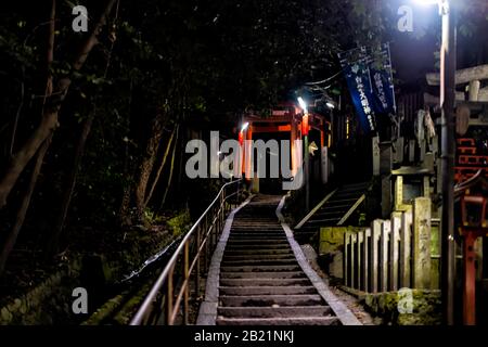 Kyoto, Japon - 11 avril 2019: Sentier d'entrée du bâtiment du sanctuaire de Fushimi Inari rouge dans le parc du jardin la nuit avec sentier de marche à travers les portes torii Banque D'Images