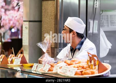 Kyoto, Japon - 17 avril 2019: Chef de cuisine servant dans les magasins du marché Nishiki vendeur de nourriture vendant des bonbons mochi de gâteau de riz Banque D'Images