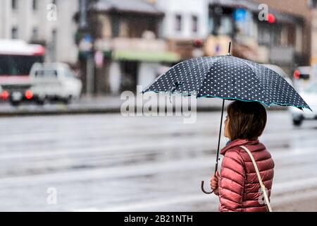 Kyoto, Japon - 9 avril 2019: Rue GOJO-dori près du district de Gion pendant les jours de pluie et les voitures de fond en circulation avec une femme tenant un parapluie sur le sidew Banque D'Images