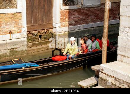 Touristes dans une gondole sur un petit canal. La ligne d'eau haute et les dommages peuvent être vus sur le bâtiment. RMN Banque D'Images